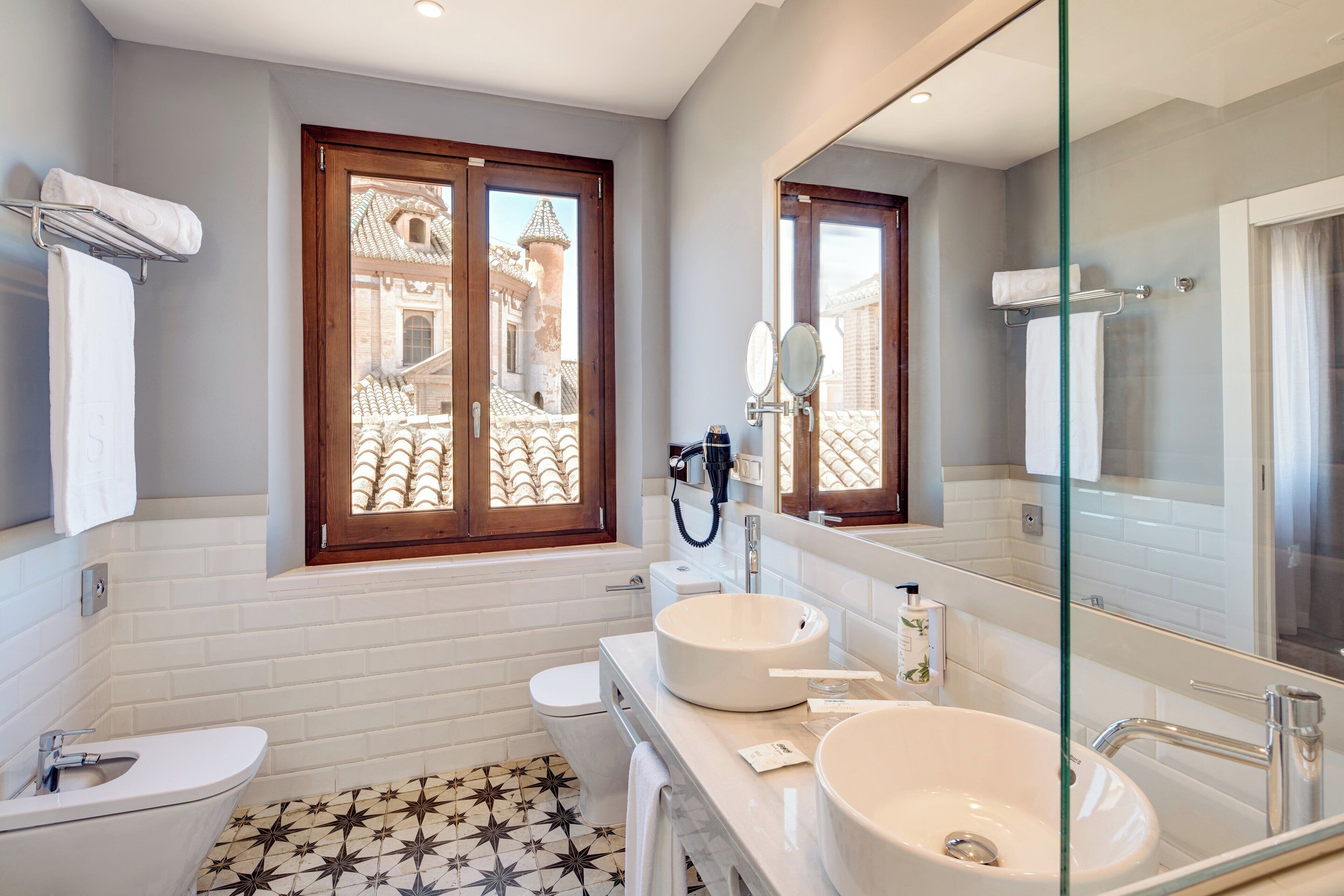 A modern bathroom with two sinks, a toilet, and a large mirror.