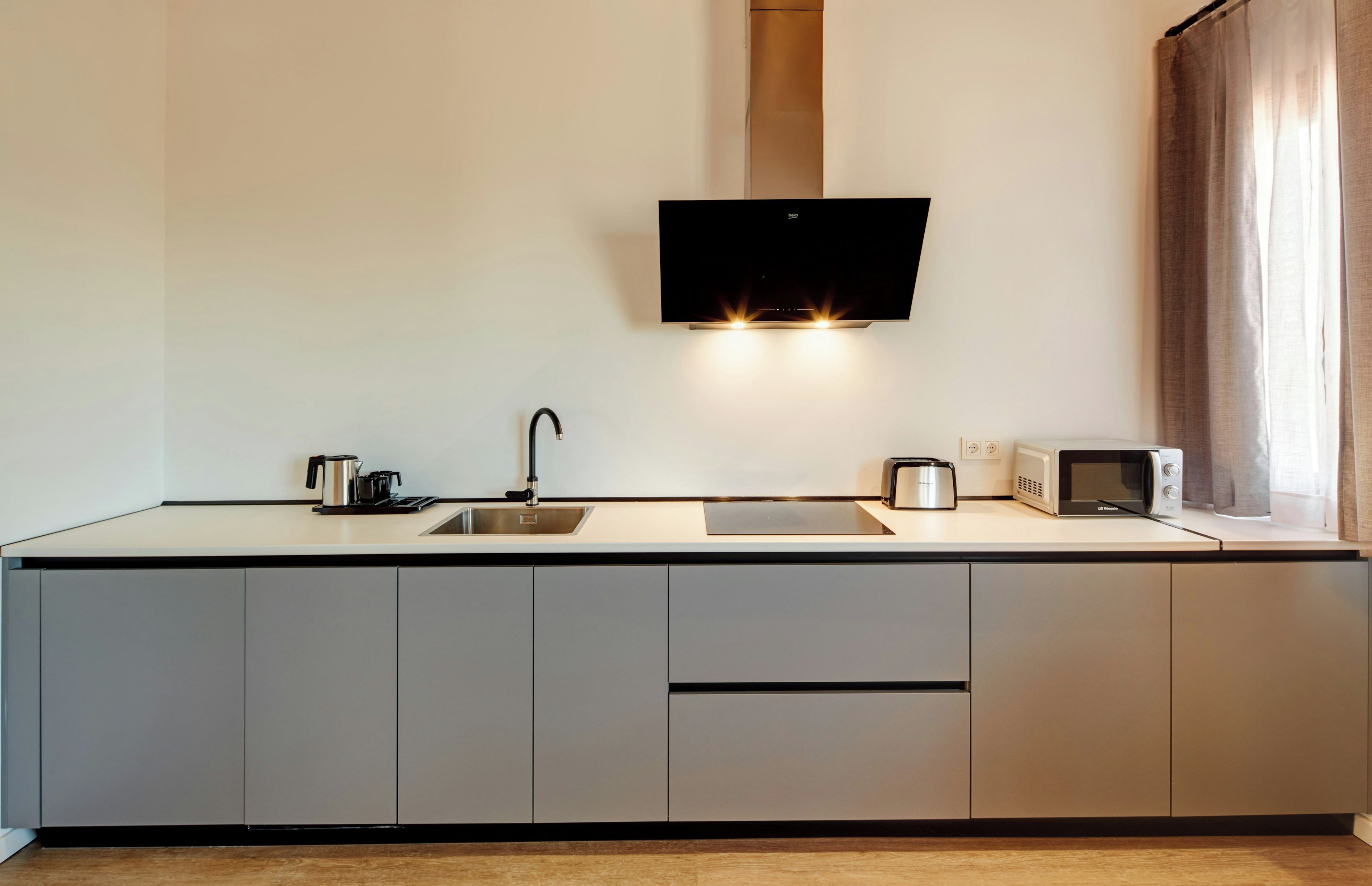 Eine moderne Küche mit Flachbildfernseher über der Arbeitsfläche, einem Spülbecken und einem Toaster.