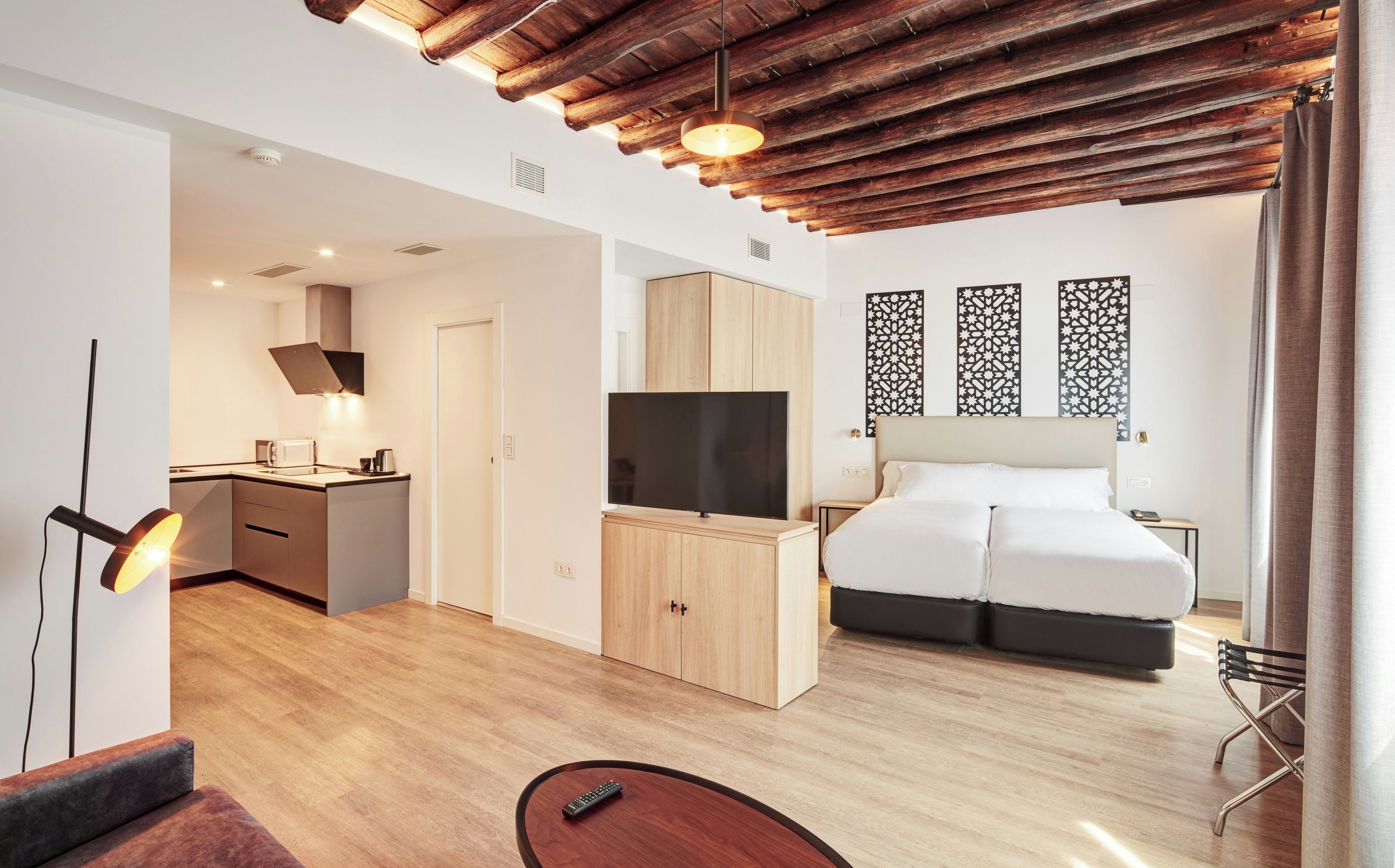 Una habitación de hotel moderna con techo de madera, un televisor de pantalla plana, una cama, un escritorio y una silla.