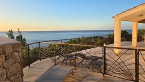 A terrace with a view of the sea, outdoor furniture, and a covered area.