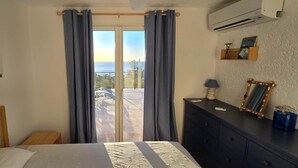 A bedroom with a bed, a dresser, a mirror, and a view of the outdoors through a sliding door.