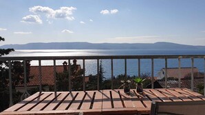 A balcony with a view of the sea and distant mountains. - Holiday apartment with balcony, WiFi and air conditioning (Novi Vinodolski)
