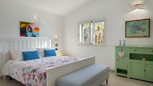 A bedroom with a bed, a bench, a green dresser, and two wall-mounted lamps. - Villa Olimpia 6+2, Emma Villas (Castellammare del Golfo)