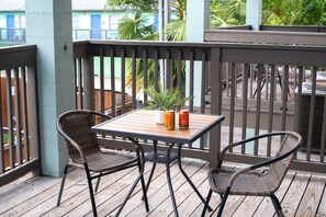 A wooden deck with two wicker chairs and a small table. - 201, Ocean Side, Patio, Laundry, Desk (South Padre Island)