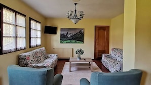 Sala de estar com dois sofás estampados, uma mesa de centro e um quadro na parede.
