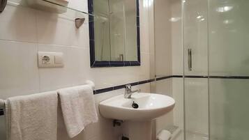 A bathroom with a white sink, a mirror, and a glass shower enclosure.