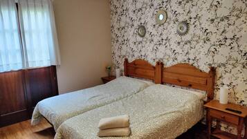 Cama doble con colcha estampada, cabecero de madera y dos mesitas de noche con lámparas.