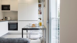 Une cuisine moderne équipée d’un four à micro-ondes Bosch, d’une machine à café et d’une table en verre sur laquelle sont disposés des aliments pour le petit-déjeuner.