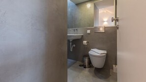 Ein modernes Badezimmer mit Waschbecken, Toilette und Mülleimer.