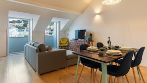Et moderne opholdsrum med spiseplads, en sofa, en gul stol og et fjernsyn.