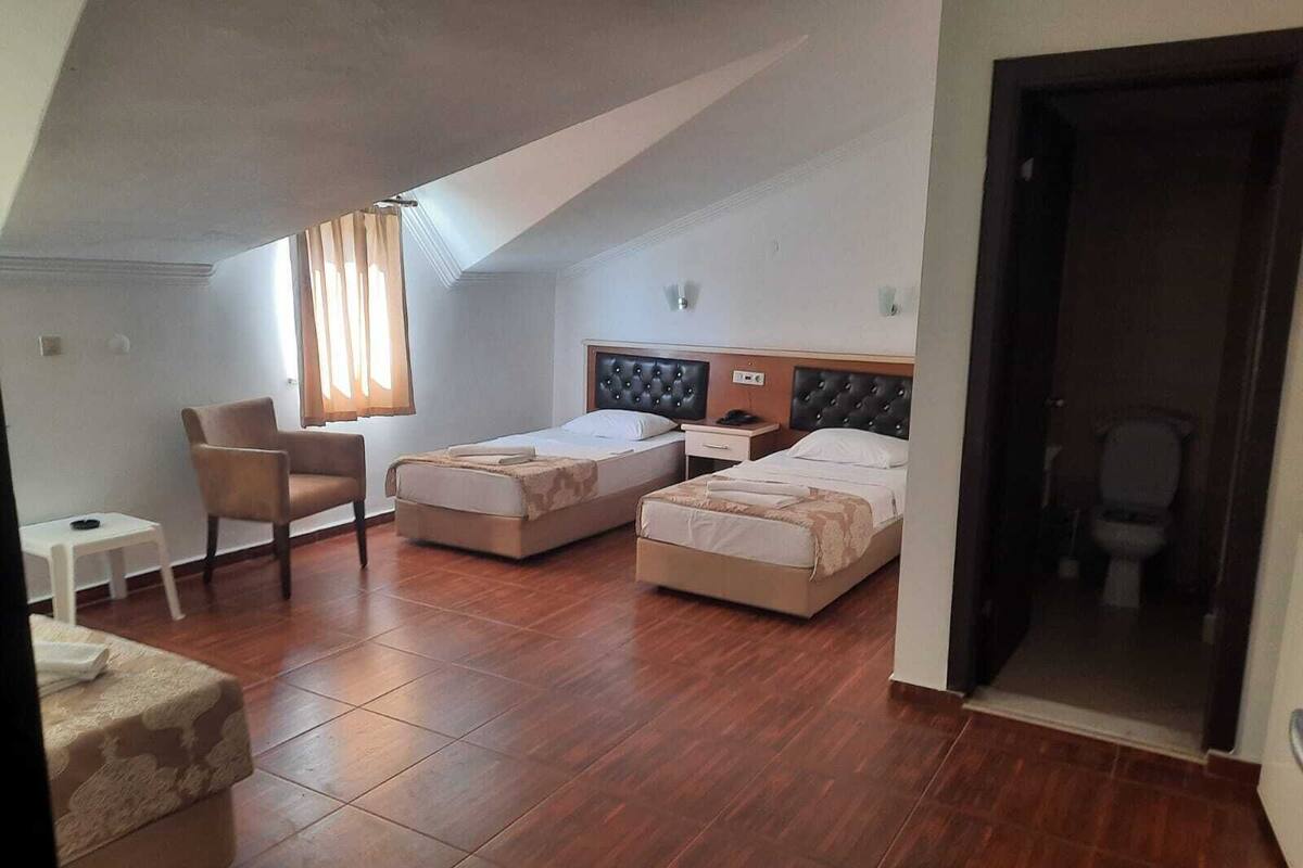 A bedroom with two beds, a chair, a small table, and a window with curtains.
