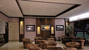 Eine Lobby mit Sofas, einem Fernseher, gerahmten Bildern und einem Schild für ein Restaurant.