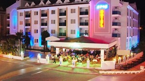 Ein mehrstöckiges Hotel mit einer überdachten Außenbestuhlung.