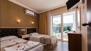 Ein Hotelzimmer mit zwei Betten, einem Fernseher, einem Schreibtisch und einem Balkon mit Blick.