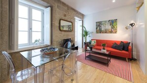 A modern living room with a red sofa, clear glass dining table, and a stone accent wall. - Modern Vitoria Getaway by LovelyStay (Porto)
