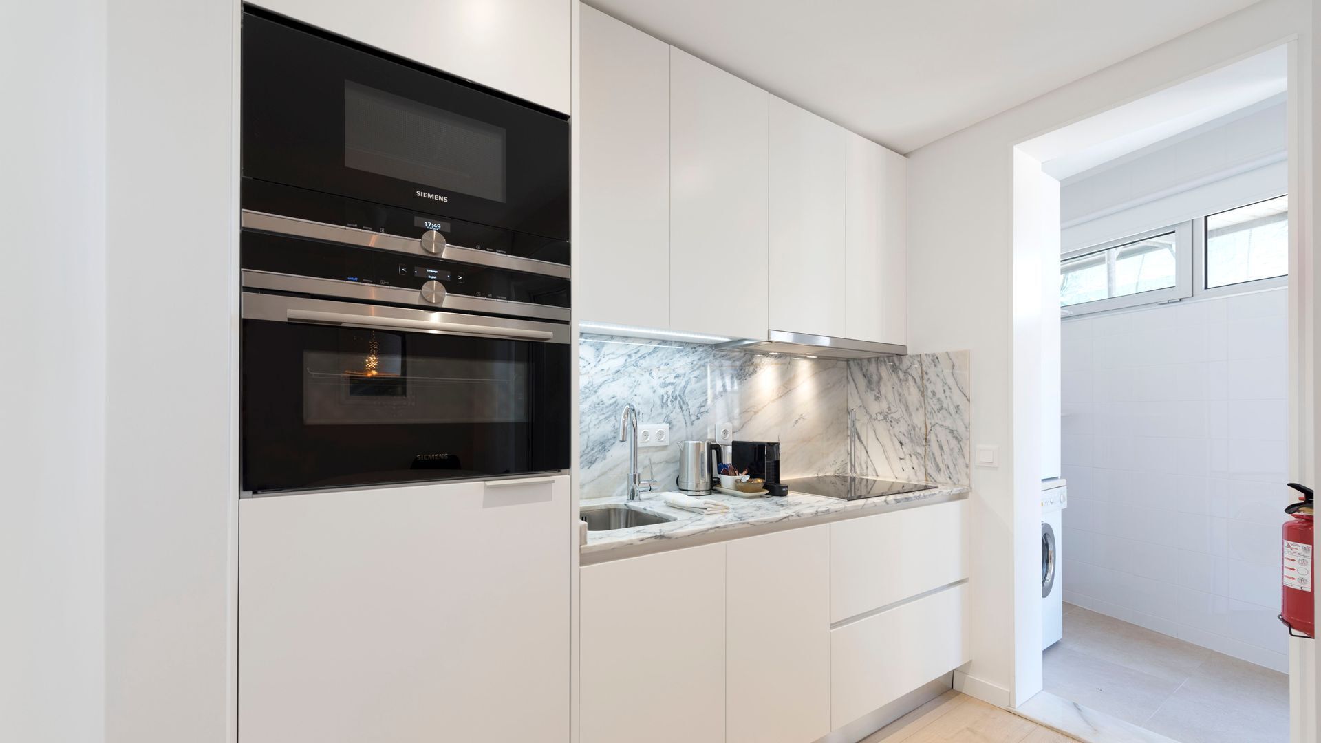 Een moderne keuken met inbouwapparatuur, een marmeren spatwand en een strak design.
