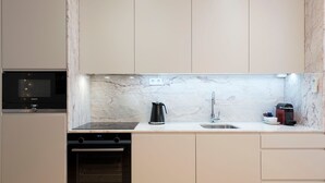 Een moderne keuken met een ingebouwde magnetron, koffiezetapparaat en vaatwasser.