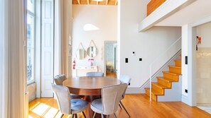 A modern dining area with a round table and chairs, a staircase, and a minimalist interior design.