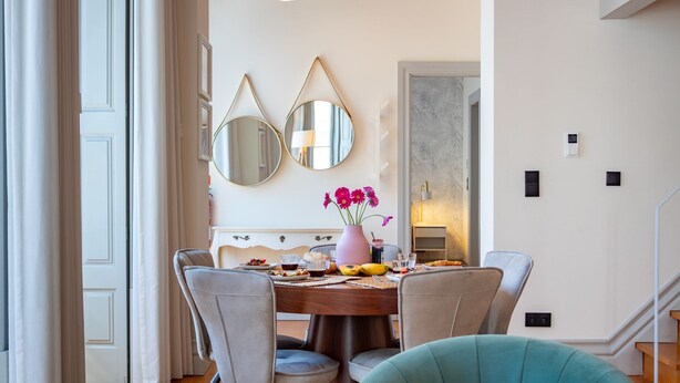 A dining area with a round table, chairs, and a vase with flowers. There are two wall-mounted mirrors above the table. - Luxurious Duplex with Unique View by LovelyStay (Porto)