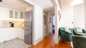 Una cucina moderna con frigorifero in acciaio inossidabile, mobili bianchi e pannello di marmo a rivestimento.