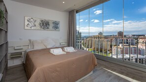 Ein modernes Schlafzimmer mit einem großen Bett, Blick auf die Stadt und einem dekorativen Wandbild.