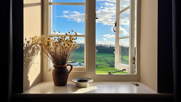 Una ventana con vista a un campo verde y un cielo despejado.