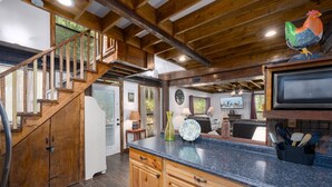 A kitchen with wooden cabinets, a granite countertop, and a wooden staircase. - Enchanting Lake Texoma Cabin with Hot Tub (Pottsboro)