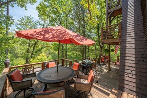 A wooden deck with outdoor furniture, a grill, and a large umbrella.