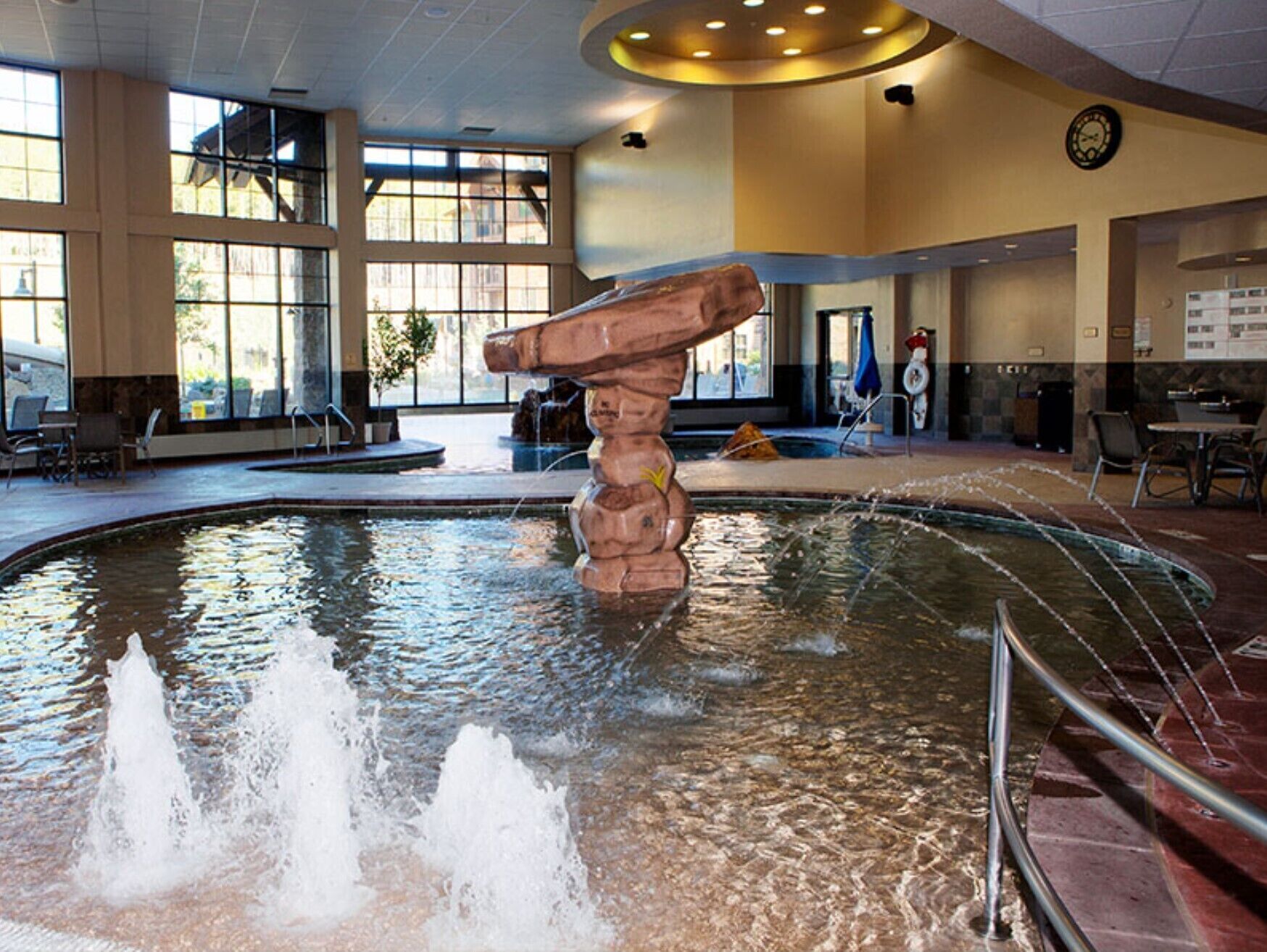 A large indoor pool with a central rock formation and multiple water jets.