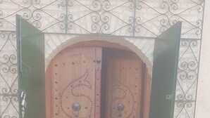 A wooden door with intricate metalwork and a keyhole, set against a patterned wall. - JARDIA beautiful vacation villa in the heart of the palm grove (TOZEUR)