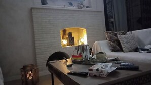 A living room with a fireplace, a sofa, a coffee table, and a lamp. - JARDIA beautiful vacation villa in the heart of the palm grove (TOZEUR)