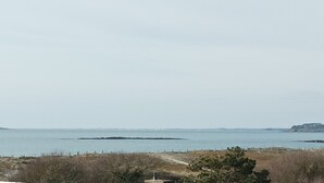 A coastal landscape with a view of the sea, a distant island, and a rocky outcrop. - Apartment with sea view 100m from the beach 2* (2*) (Saint-Gildas-de-Rhuys)