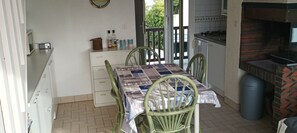 A kitchen with a dining table, chairs, a stove, and a trash bin.