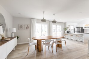 Una cucina moderna con mobili bianchi, un tavolo da pranzo in legno e illuminazione a sospensione.