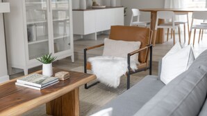 A modern living room with a wooden coffee table, a grey sofa, and a brown leather armchair. There is a bookshelf with books and a small plant on the table. - Serene home with all the comforts of a fully designed space- 3 🛏/2 🛁 House (Chesterfield)