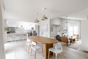 Una cucina moderna con mobili bianchi, un tavolo da pranzo in legno e sedie bianche.