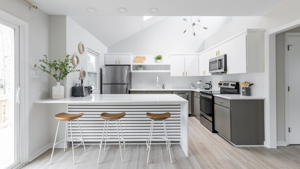 A modern kitchen with a central island, bar stools, stainless steel appliances, and a large window. - Serene home with all the comforts of a fully designed space- 3 🛏/2 🛁 House (Chesterfield)