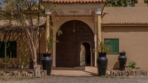 Una entrada amb una porta de fusta gran, un teulat de rajola i plantes en testos.