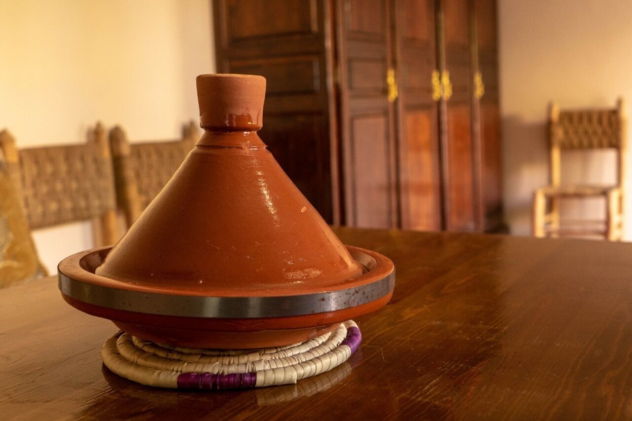 A traditional Moroccan tagine on a wooden table with woven coasters.