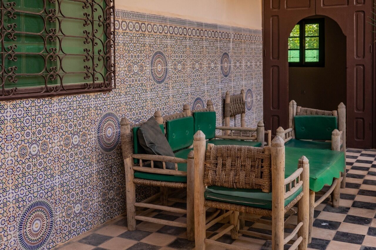 Una habitación con piso a cuadros, pared de azulejos decorativos y un sofá tapizado en verde con un plaid.