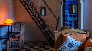 Un escalier orné d’une rampe décorative, une chaise avec un coussin et une petite table avec une lampe.