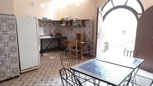 Une cuisine de taille réduite, agrémentée de carreaux décoratifs, avec une table à manger, des chaises et un réfrigérateur.