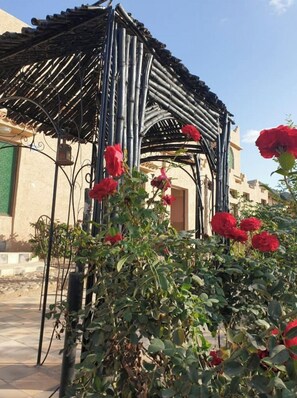 Situated in a lush garden, this traditional gazebo offers a serene setting surrounded by vibrant flowers and greenery.