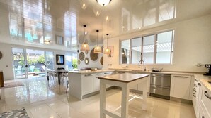 Una cocina amplia con una isla central, ventanas grandes e iluminación colgante moderna.