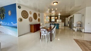 Una cocina amplia con electrodomésticos modernos, un comedor con sillas blancas y un mural decorativo grande.