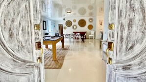 Una habitación amplia con techo alto, un comedor con mesa y sillas, y decoración artística en las paredes.
