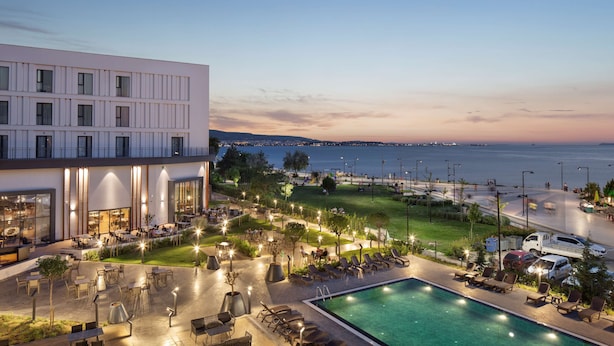 Un hotel con piscina, mobiliario exterior y vista al mar.