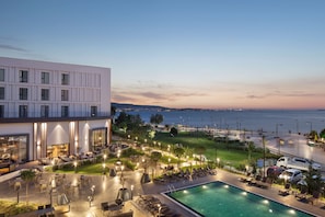 A hotel with a pool, outdoor seating, and a view of the sea.