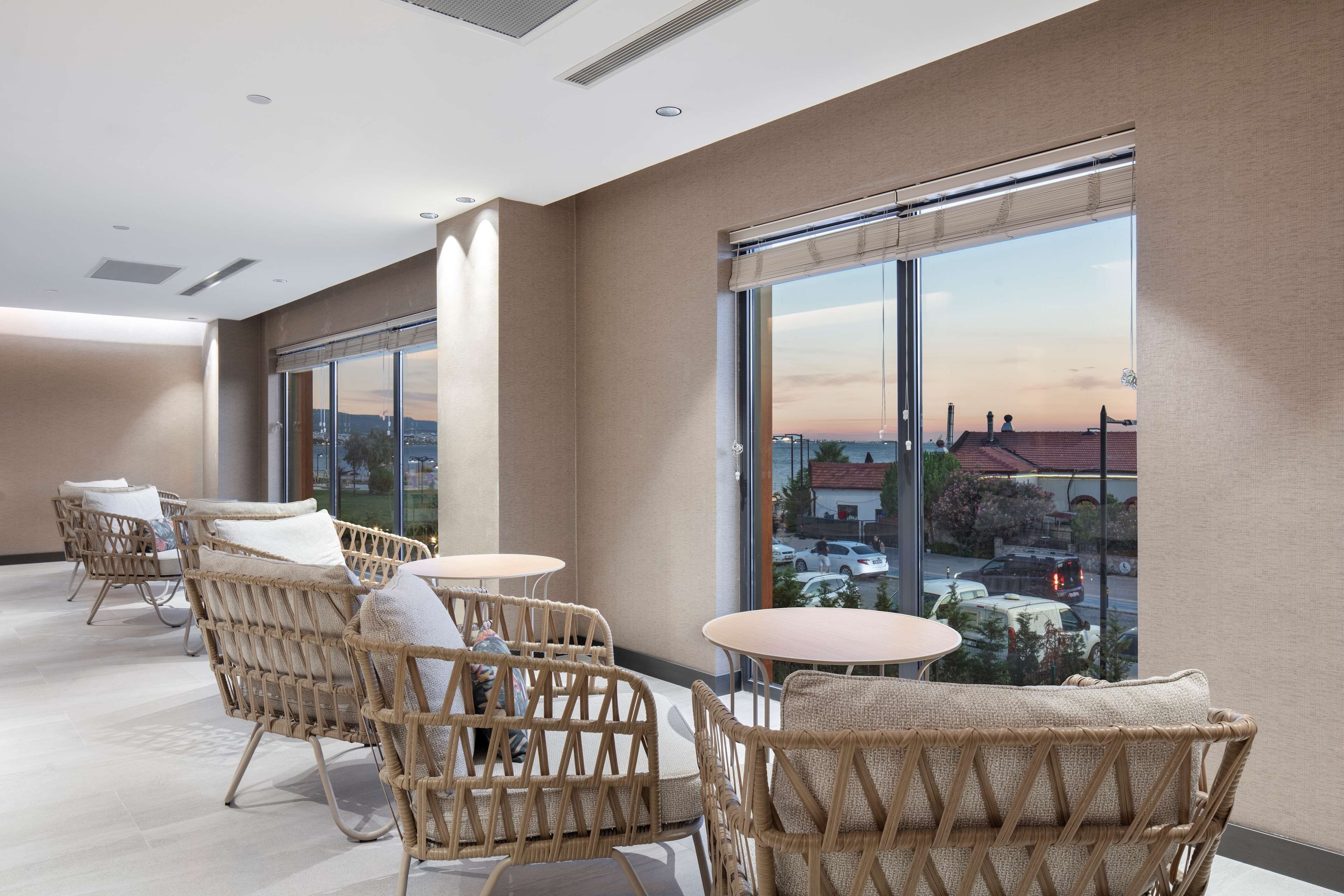 Una habitación de hotel moderna con muebles de mimbre, ventanas amplias y vistas a la ciudad.