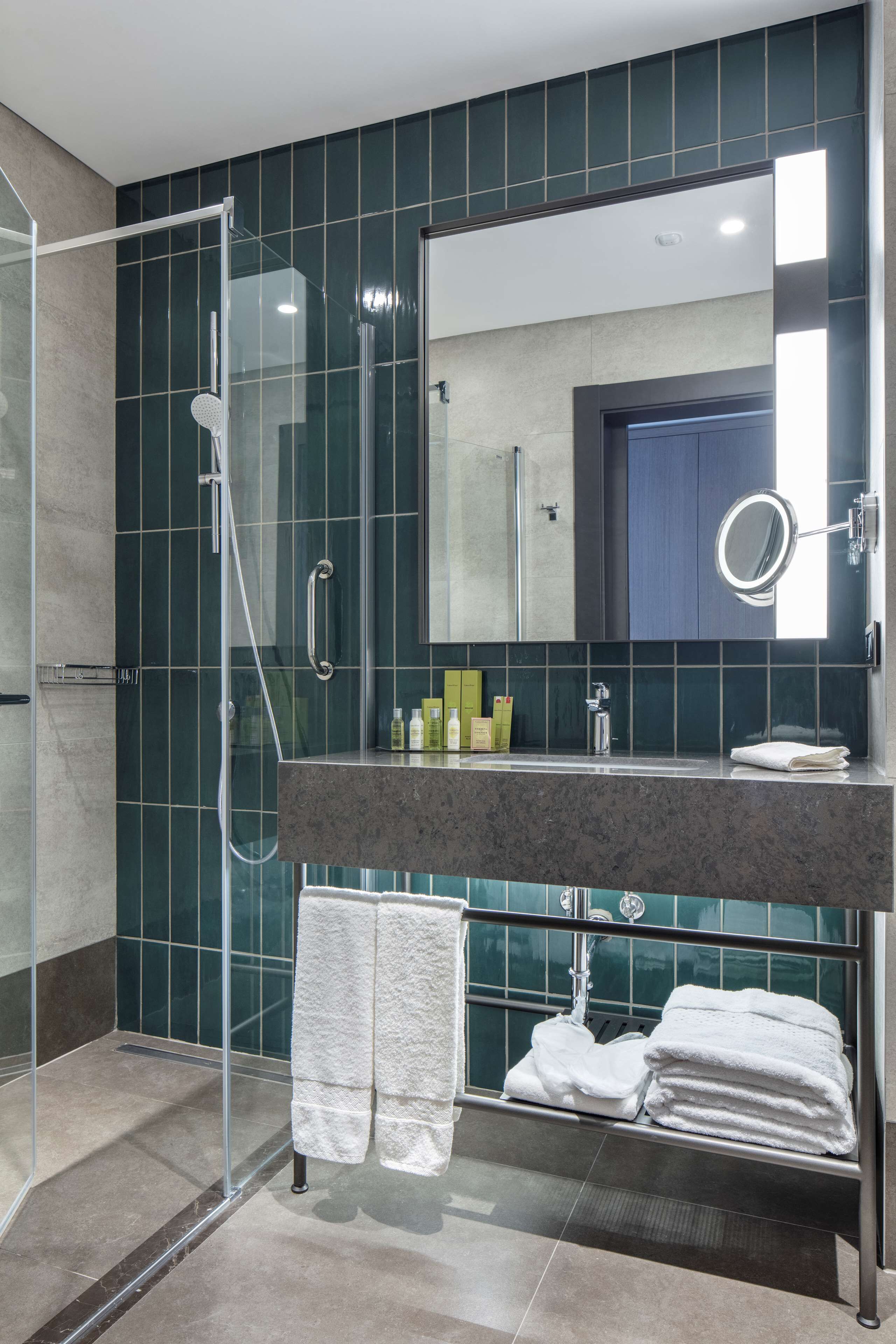 A modern bathroom with a glass-enclosed shower, a marble countertop, and a large mirror.